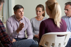 Members Of Support Group Sitting In Chairs Having Meeting